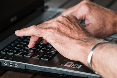 Mains de senior au travail sur un clavier d'ordinateur